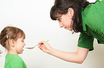 A woman giving medication to a young girl