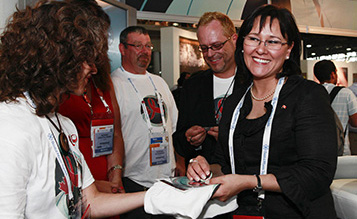 La ministre de la Sant� Leona Aglukkaq re�oit un tee-shirt et un macaron de la part de b�n�voles pendant sa visite du stand d�exposition du Canada � la XVIIIe Conf�rence internationale sur le sida tenue � Vienne en Autriche. (La Presse canadienne Images PHOTO/AP/Lilli Strauss)